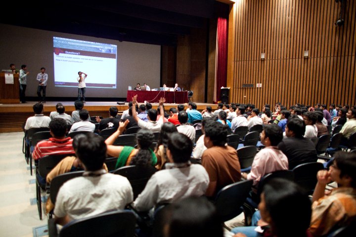 a group of people sitting in front of a screen on a room