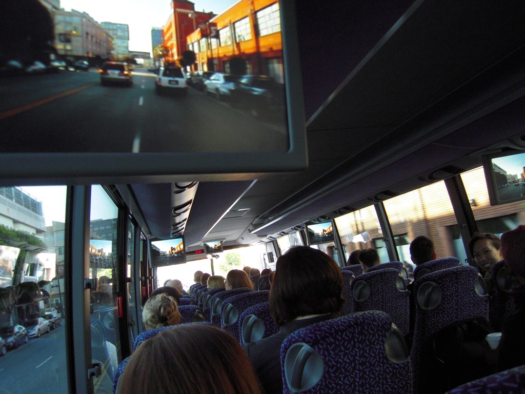 an outdoor bus with many people inside on a sunny day