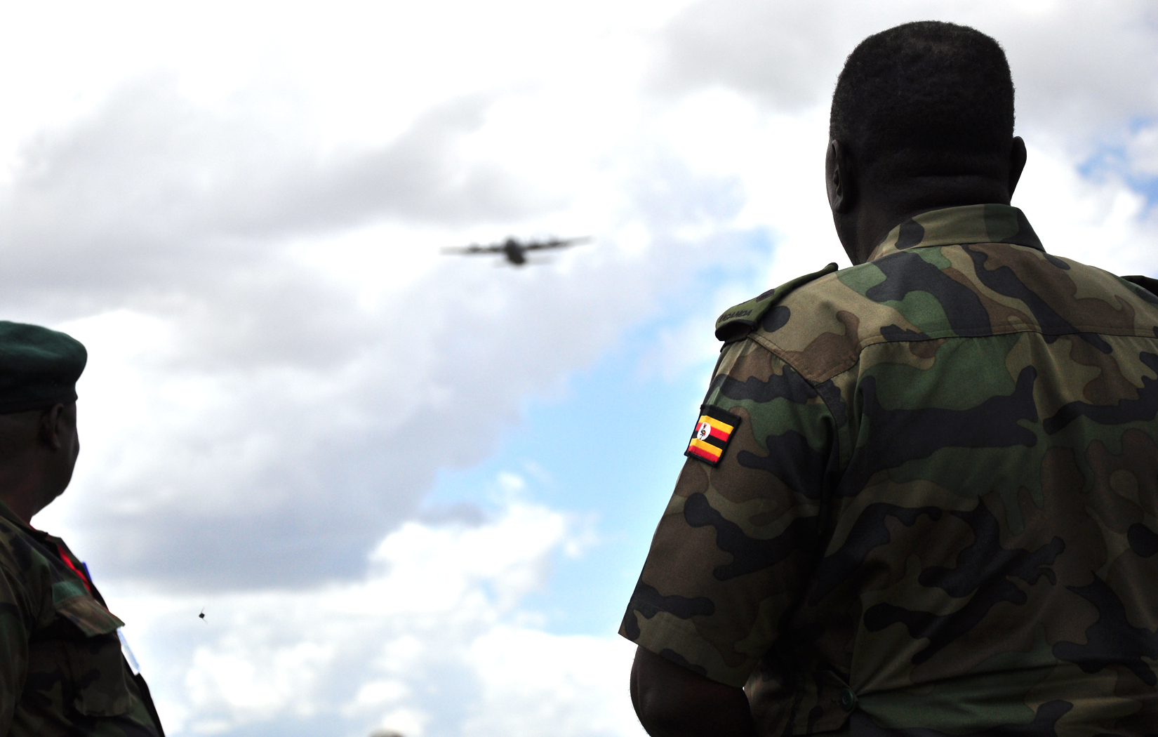 two soldiers standing next to each other in front of a sky with an airplane