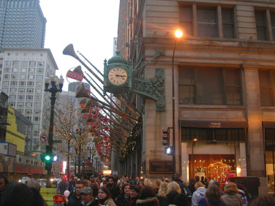 people are standing in the street near the clock