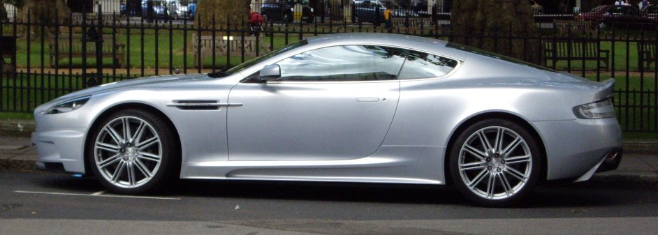 a silver sports car parked next to a black fence