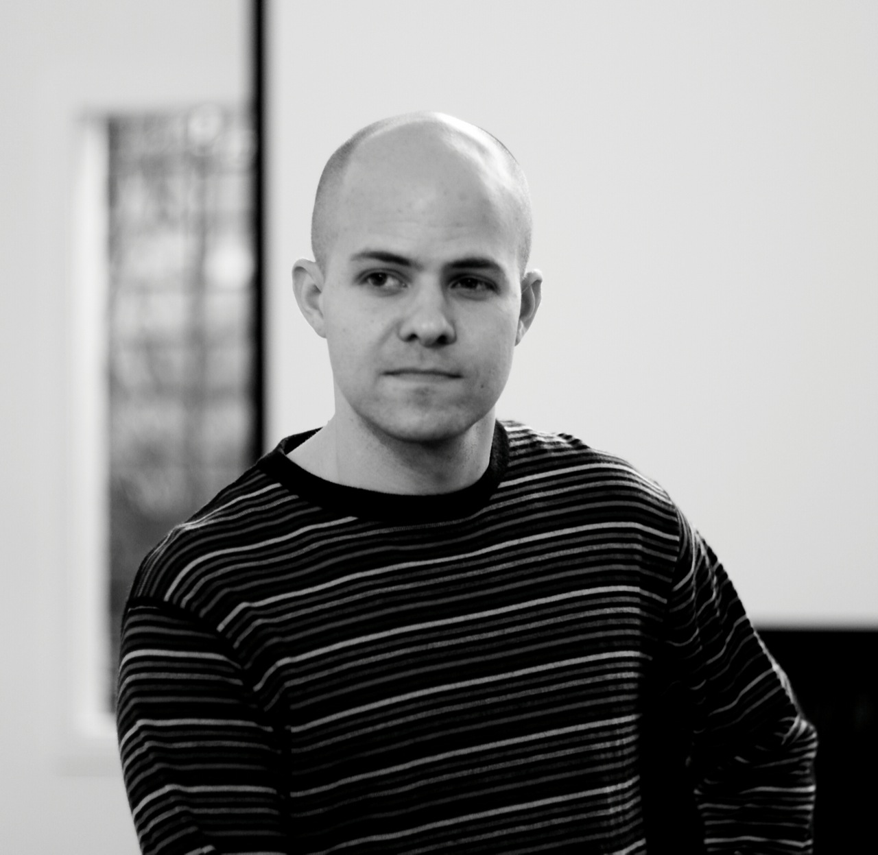 man with bald hair looking at camera in black and white po