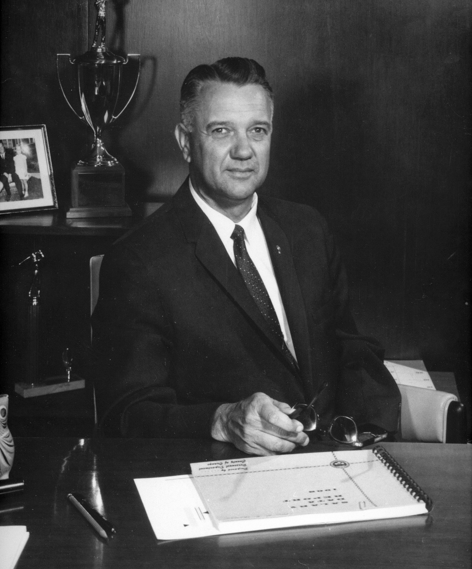 a man with an elegant black suit and tie sits at a desk