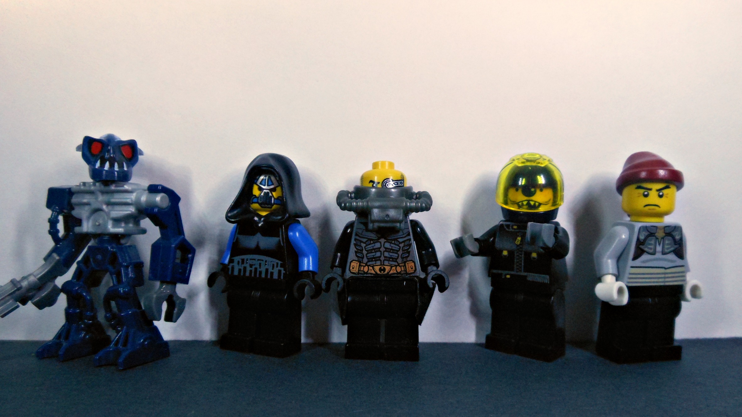 five legos of different types and sizes standing on a black surface