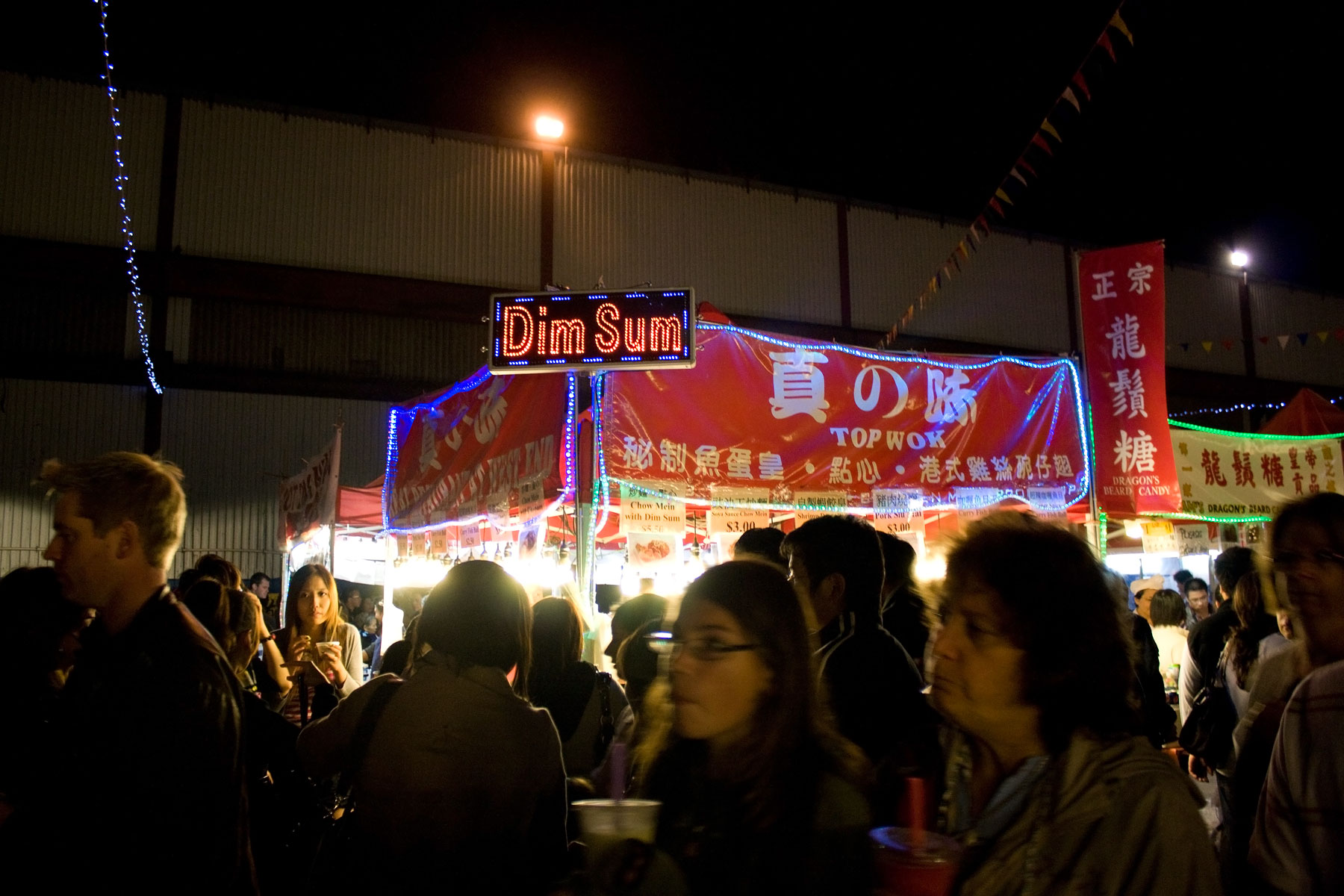 several people stand in a line at an outdoor market