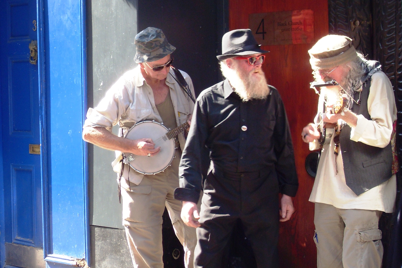 three bearded men playing instruments on the street