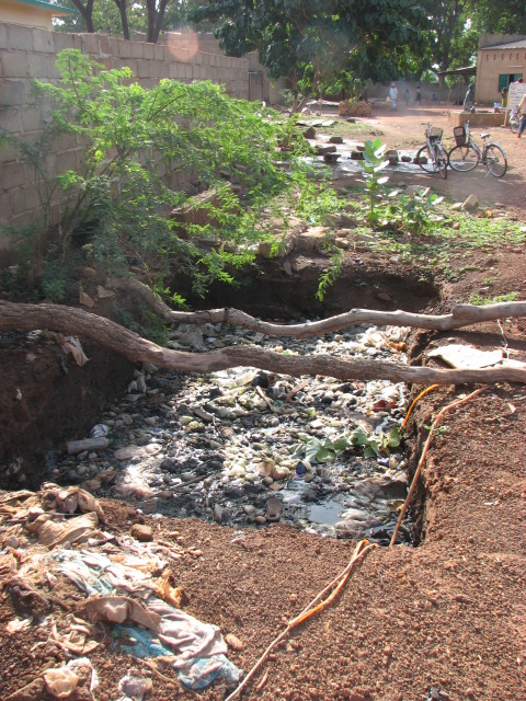 a very dirty river next to some people sitting on a bench