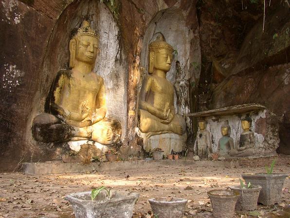 three small statues of buddhas surrounded by concrete pillars