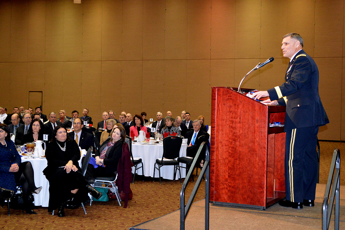 the man standing at a podium gives a speech in front of a large group of people