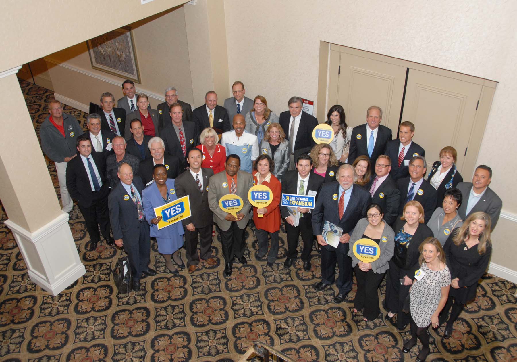 a group of people standing and sitting in a lobby holding signs