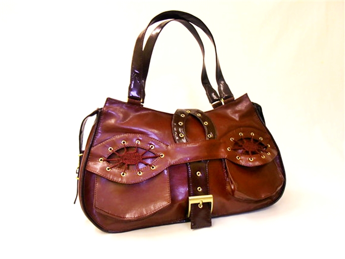 brown purse with a large decorative embellishment sitting on a white surface