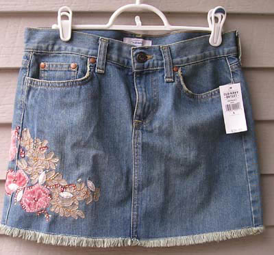 a jean skirt with flowers on it hanging up on a wall
