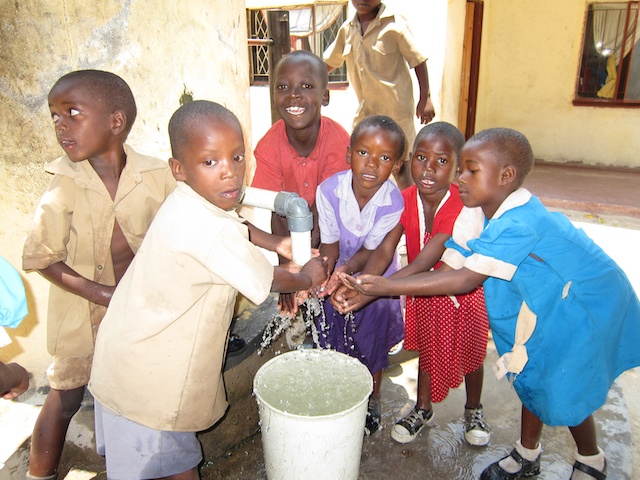 several children in a group wash their hands