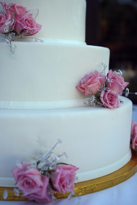 a three tiered wedding cake with pink roses on it