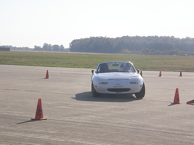 a white sports car with no hood in a parking lot with orange cones