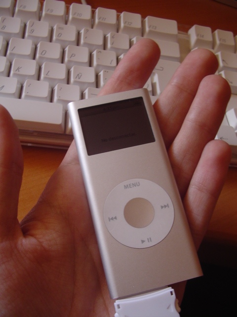 a man's hand holding a small silver ipod