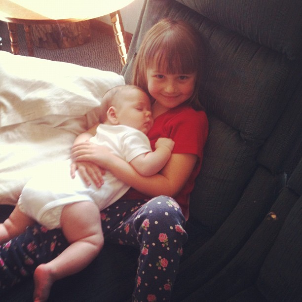 two young children cuddling on the arm of a couch