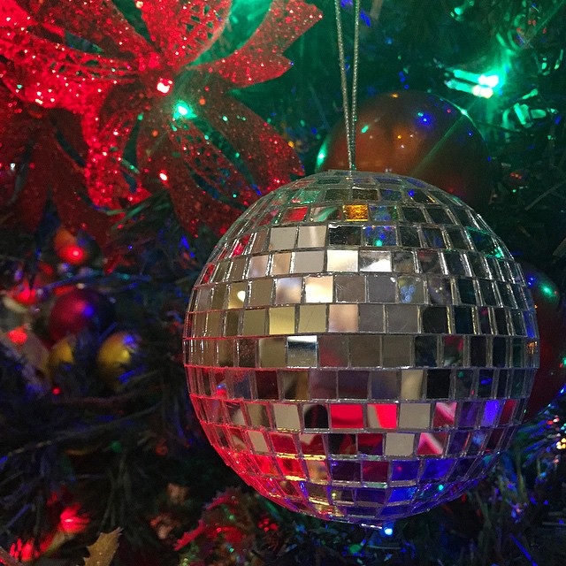 a shiny disco ball hanging on a christmas tree