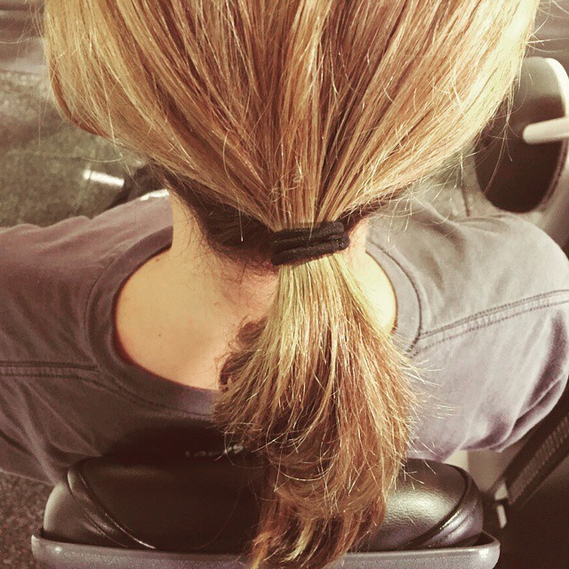 the back of a woman's head with a messy ponytail and her hair pulled in