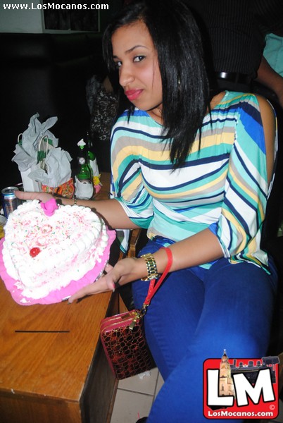 a woman holding a heart shaped cake with candles on top