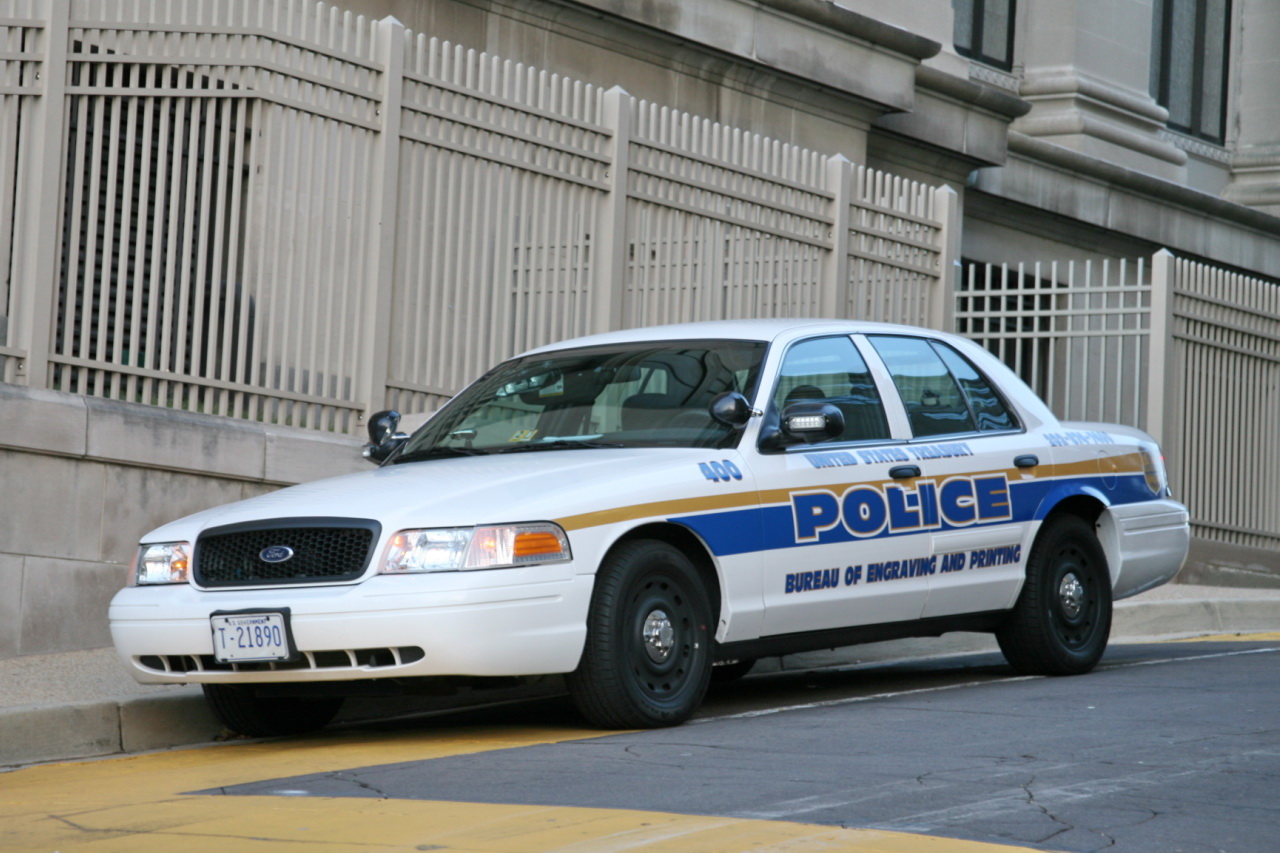 police car parked on the side of the road near a fence