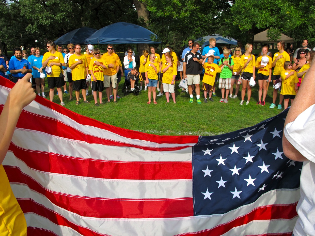 people standing behind a large american flag on a field