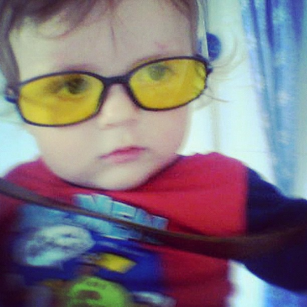 a toddler wearing glasses in front of a window