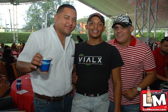 two men standing with another man holding a drink