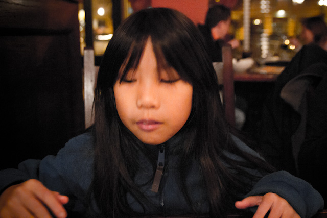 a child sitting at a table using a cell phone
