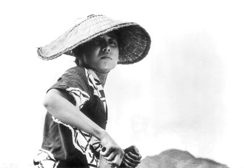 woman in a hat riding a motorcycle on the desert