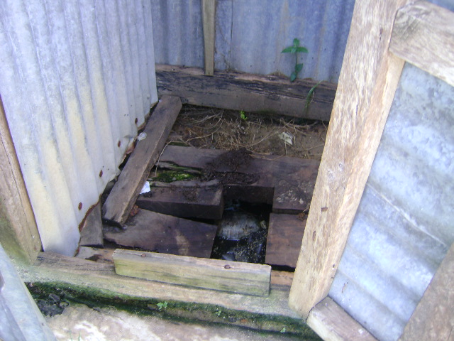 a dirty outhouse door and a hole in the ground