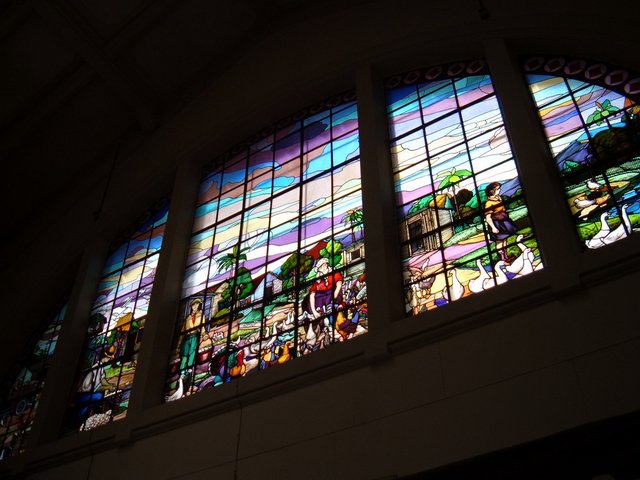 a large multicolored window above a tall white wall
