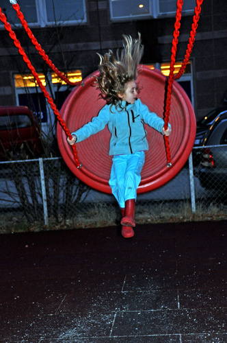 girl on the swings on the playground at night