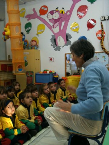 a woman teaching children in a classroom with other people