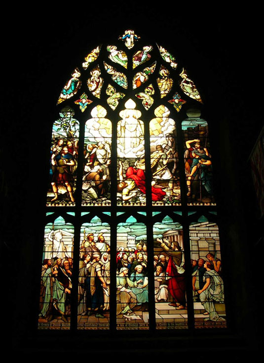 an elaborate stained glass window with figures and angels