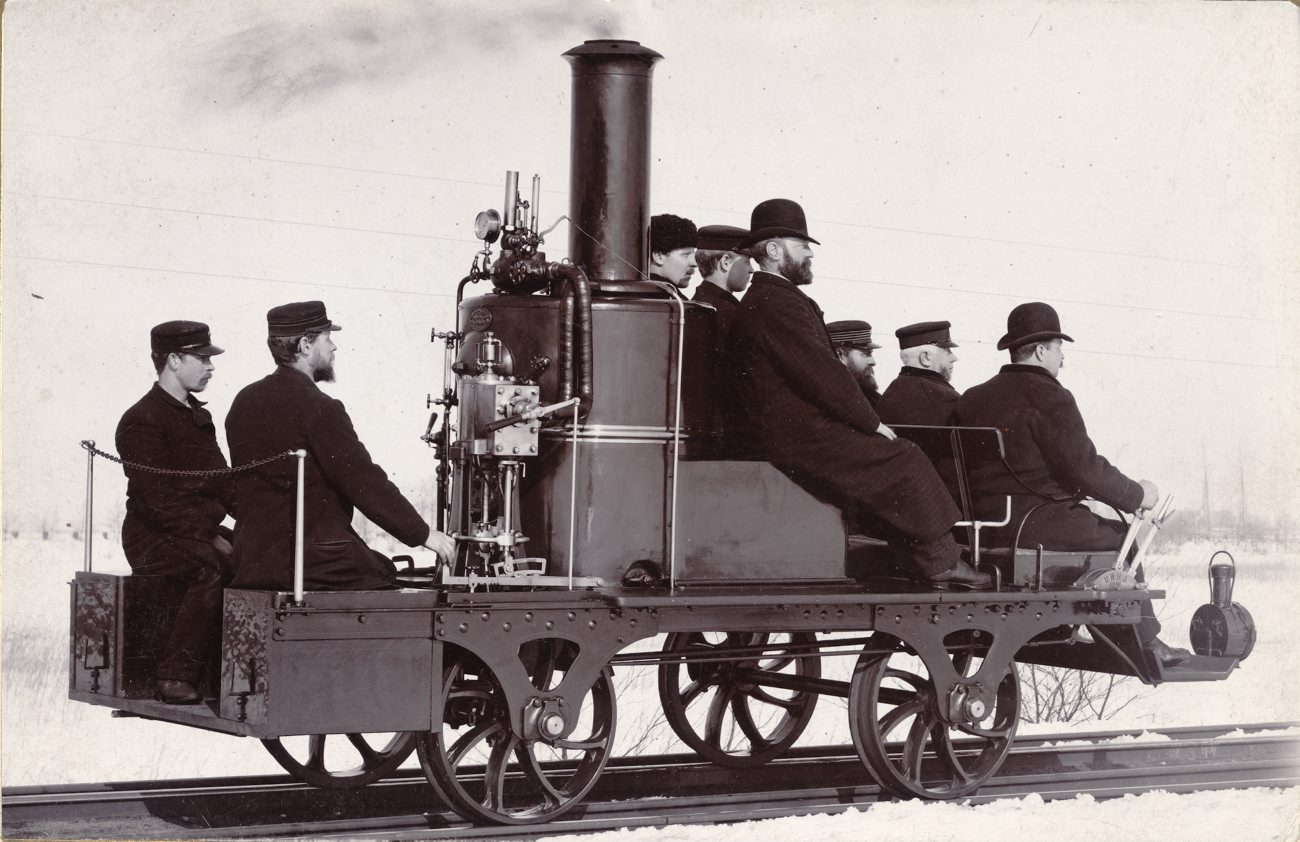 black and white pograph of men sitting on the front of a train