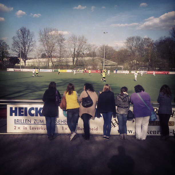 many people watching soccer in a field on a sunny day