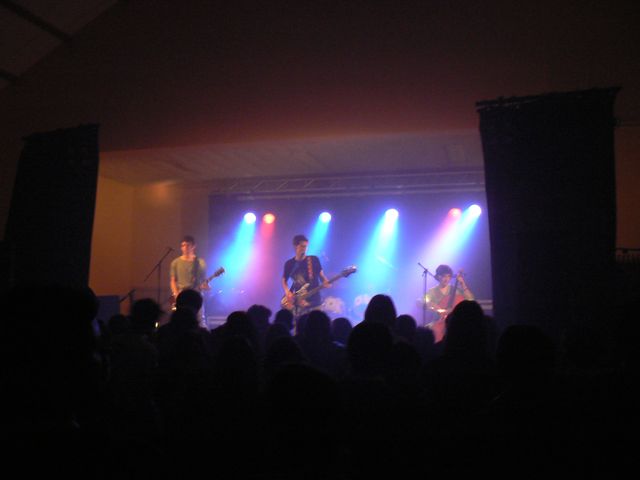 some people are standing in front of stage lights with purple and blue lighting