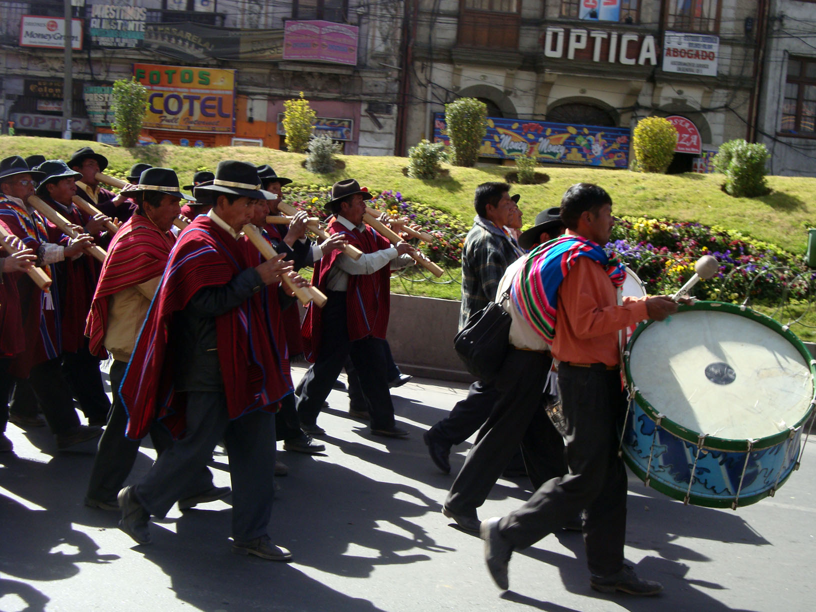 many men are marching in the street carrying wooden instrument