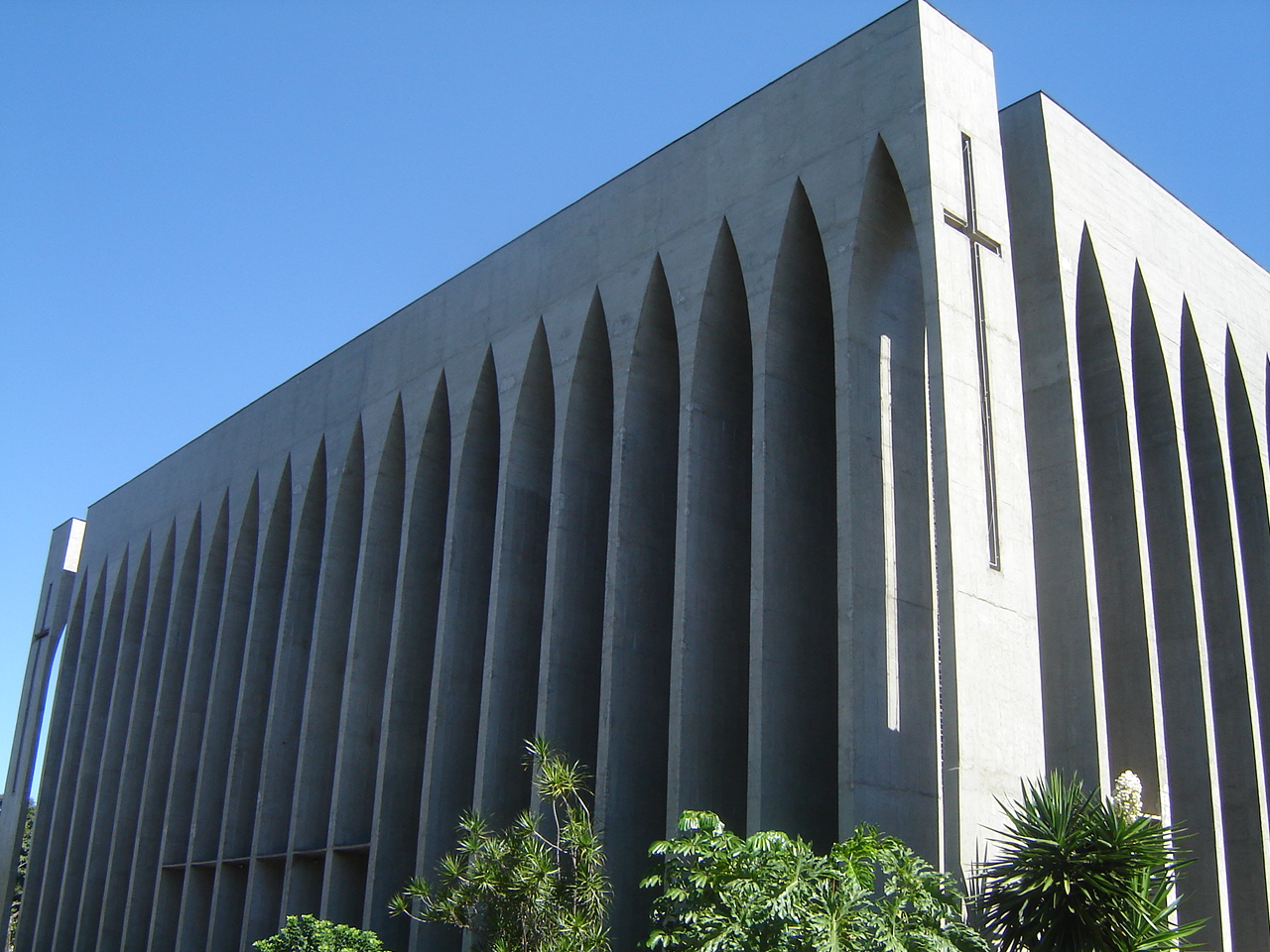 the side of a building with a steeple of architecture and a small cross on it