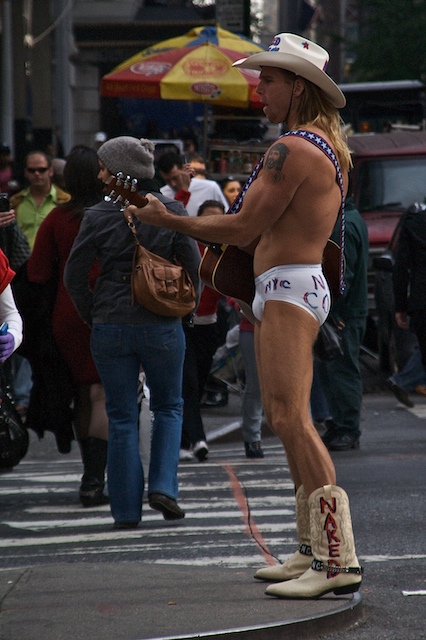 a man with long blond hair is standing in the street