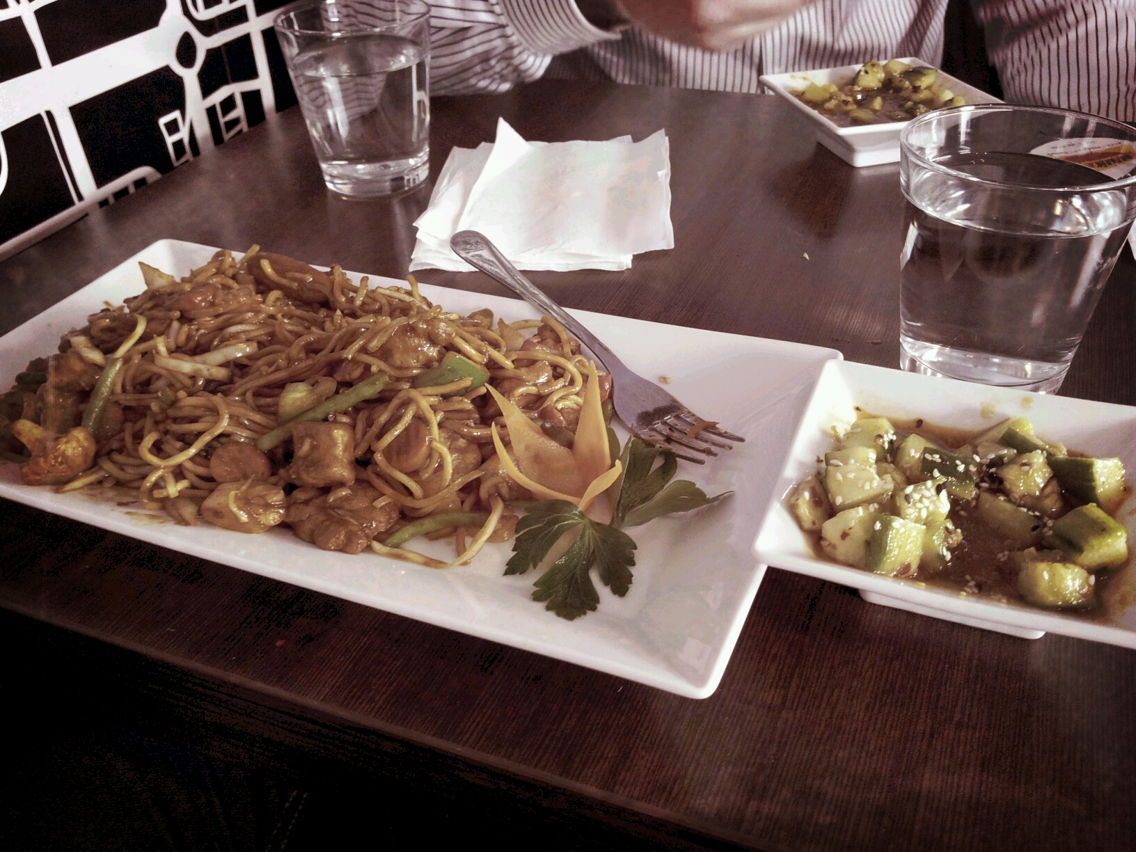 plates of food are on a table and a woman is sitting next to them