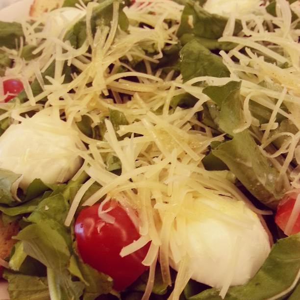 a plate of a green salad with tomatoes and parmesan cheese