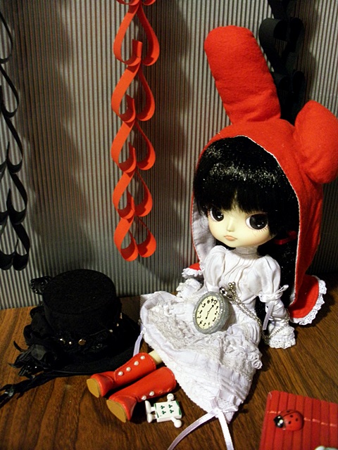 a close up of a doll sitting on a table near other items