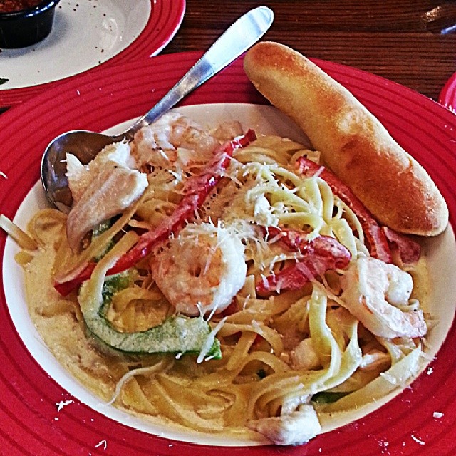 a plate of pasta with shrimp and peppers and bread