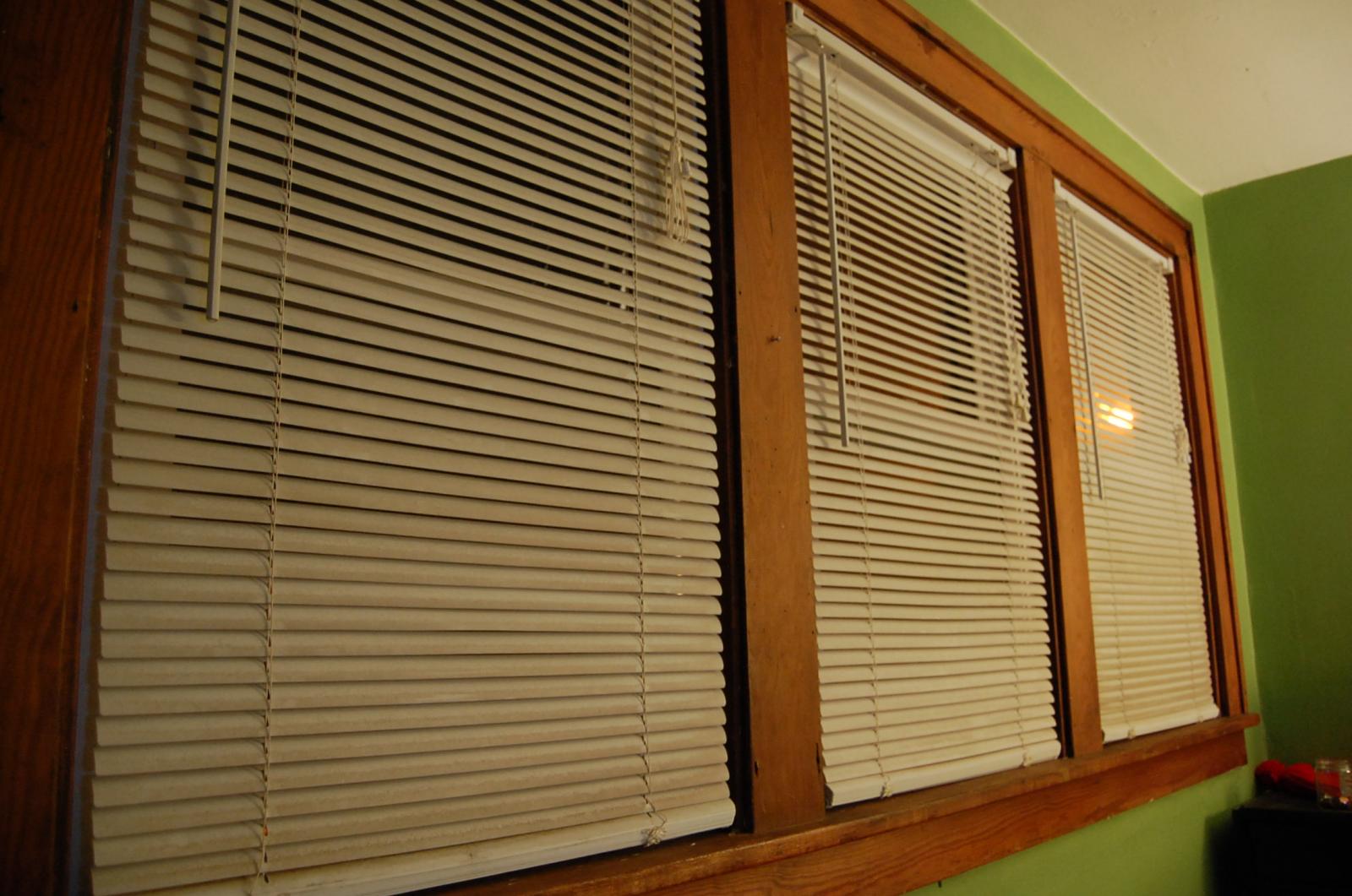 an empty room with two closed windows and green walls