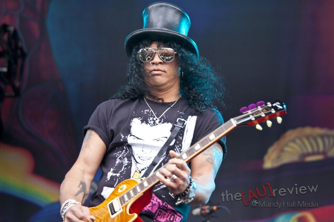 a man with blue hair and hat holding an orange guitar