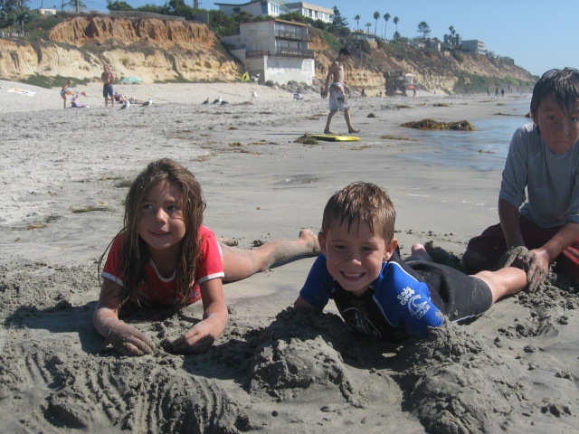 a couple of children on the beach with sand