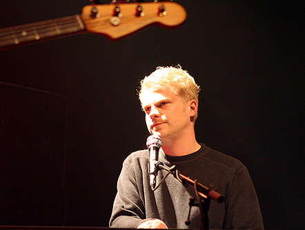 a man standing in front of a microphone with an electric guitar on it
