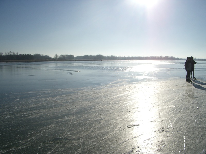 two people standing on top of ice near water